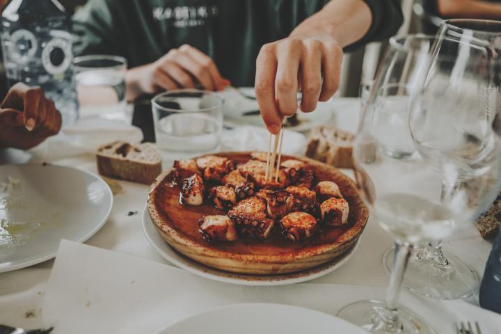 Un hombre come una ración de pulpo.