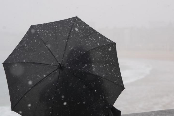 Una persona se protege del frío y el viento con un paraguas