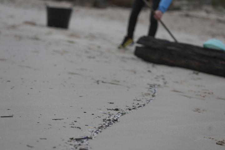 Operarios de empresas y vecinos de la zona retiran los pellets o bolitas para fabricar plástico que aparecen en las playas gallegas y de Asturias, tras la caída de un contenedor de un barco el pasado diciembre, en la playa de Area Maior en Muros.
