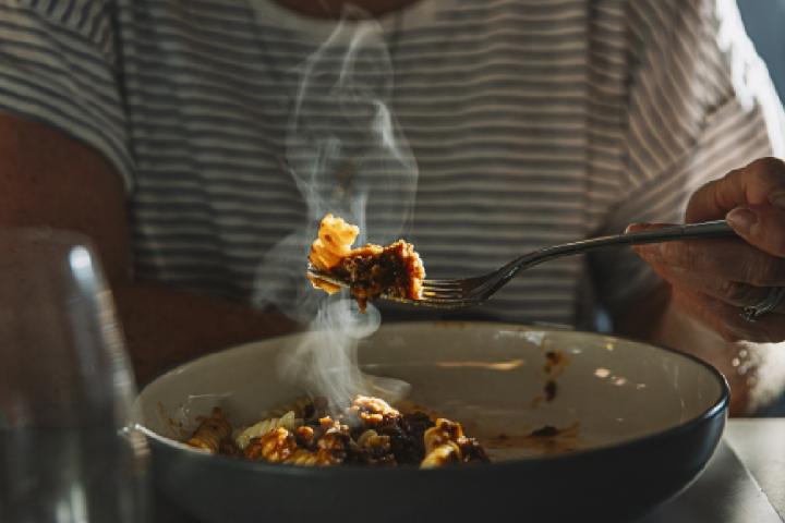 Una persona degustando un plato caliente.