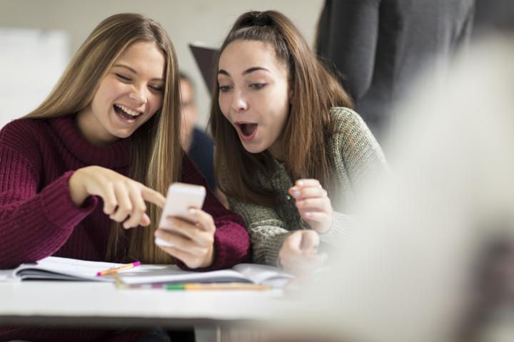 Imagen de archivo de dos adolescentes consultando el teléfono móvil en un aula.
