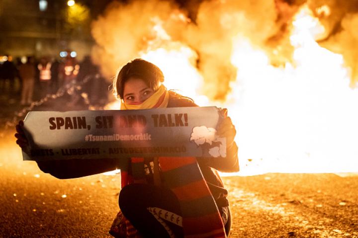 Una manifestante porta una pancarta de Tsunami Democratic durante los disturbios durante una protesta independentista, en el marco del duelo del clásico, Barcelona-R. Madrid.