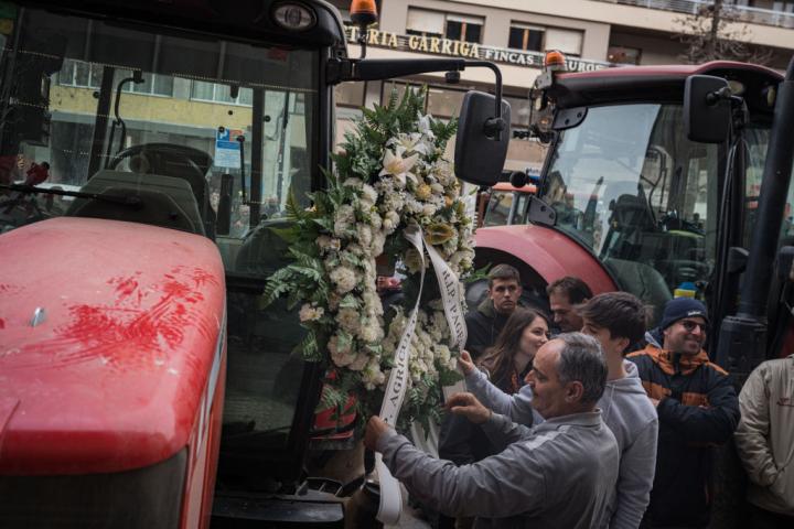 Un trabajador del campo coloca una corona fúnebre en su tractor durante unas protestas en Cataluña