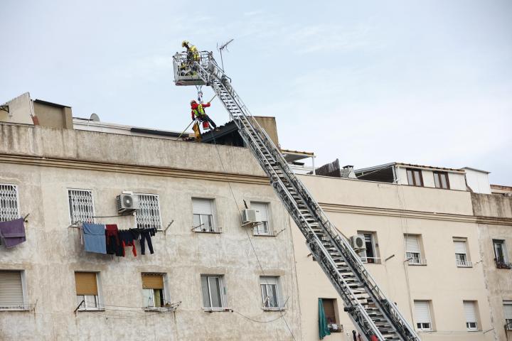Los bomberos inspeccionan el interior de un edificio de cinco pisos, el bajo y otros cuatro, que se ha derrumbado en la calle Canigó de Badalona (Barcelona), al haber cedido el forjado de la construcción.