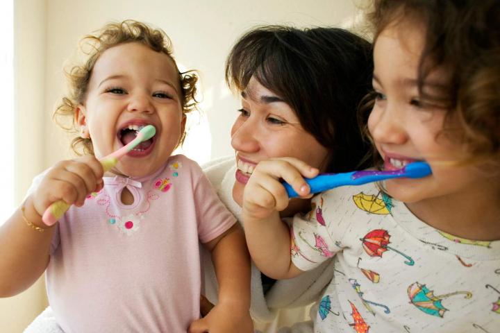 Niños cepillándose los dientes con su madre