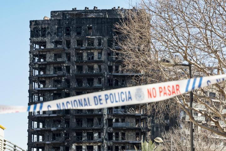 Una cinta policial impide el paso hacia los edificios afectados por un incendio ayer jueves en València, en el que de momento se contabilizan cuatro víctimas mortales, a falta de poder acceder al interior de la estructura, mientras que las personas no localizadas se sitúan en estos momentos en 14, aunque esta cifra puede ir variando conforme prosigan las investigaciones.