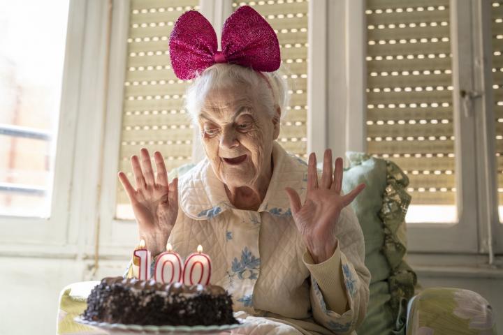 Una mujer sopla las velas en su 100 cumpleaños.