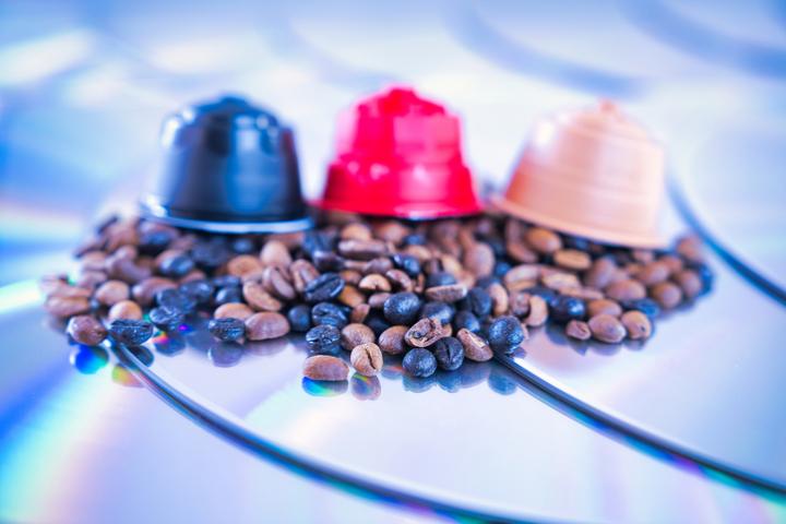 Imagen de tres cápsulas con granos de café al lado.