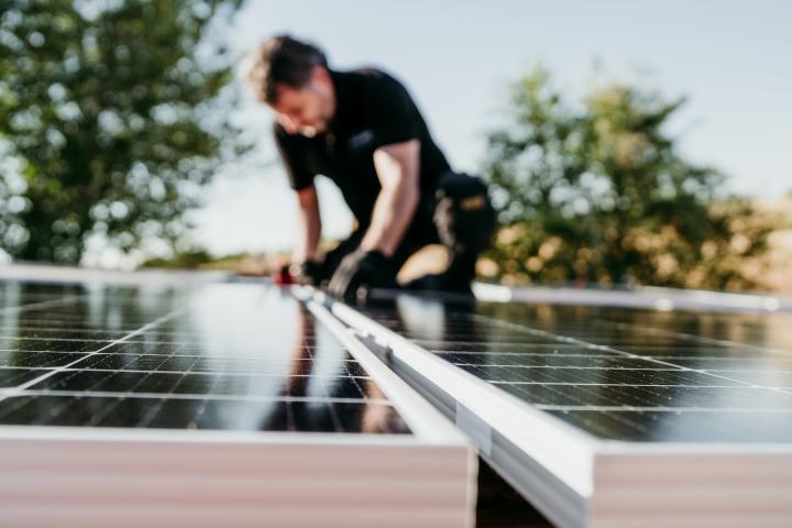 Un técnico instala varios paneles solares en el tejado de una vivienda.