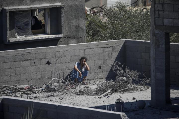 Una palestina espera sentada encima del tejado de su hogar destruido tras bombardeos israelíes, en las inmediaciones del campo de refugiados de Al Nusairat (Gaza).