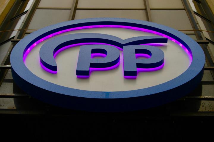 El cartel del Partido Popular en la sede de Génova, iluminado de color morado.