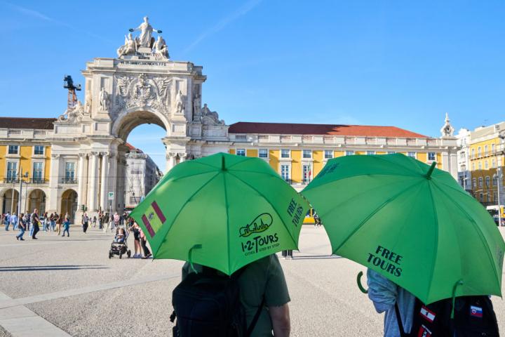 Dos guías esperan la llegada de turistas en la Plaza do Comercio de Lisboa.