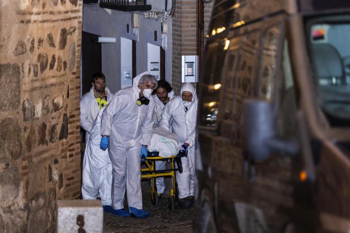 Miembros de los servicios funerarios trasportan uno de los cuatro cadáveres encontrados hoy martes en la calle Santa Leocadia de Toledo, localizados en una vivienda de la capital.