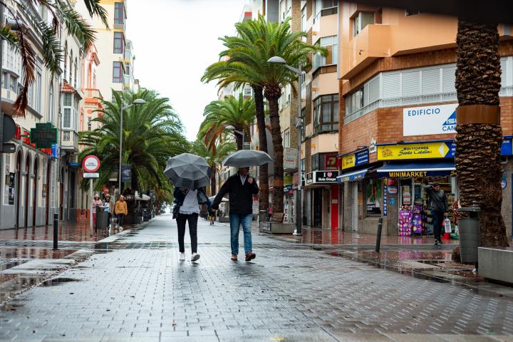 Dos personas con un paraguas, resguardándose de la lluvias en Las Palmas de Gran Canaria.
