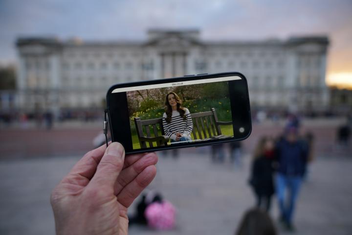 Una persona viendo el anuncio de Kate Middleton frente al palacio de Buckingham.