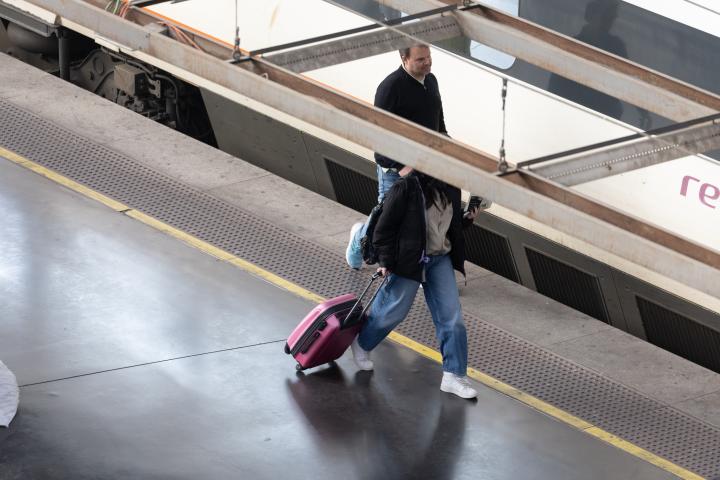 Una mujer paseando frente a un tren de Renfe.