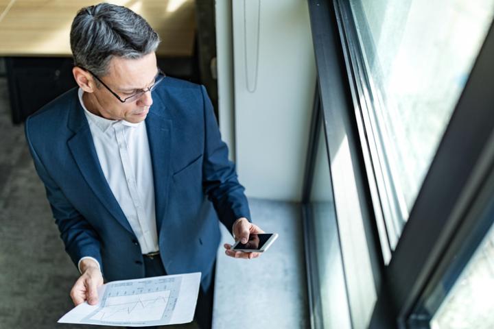 Imagen de un ejecutivo comprobando un mensaje en su teléfono móvil.
