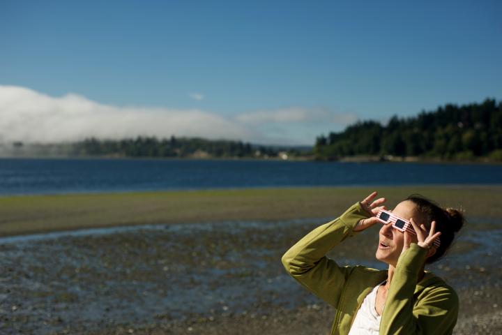 Una mujer con gafas de sol mira un eclipse.