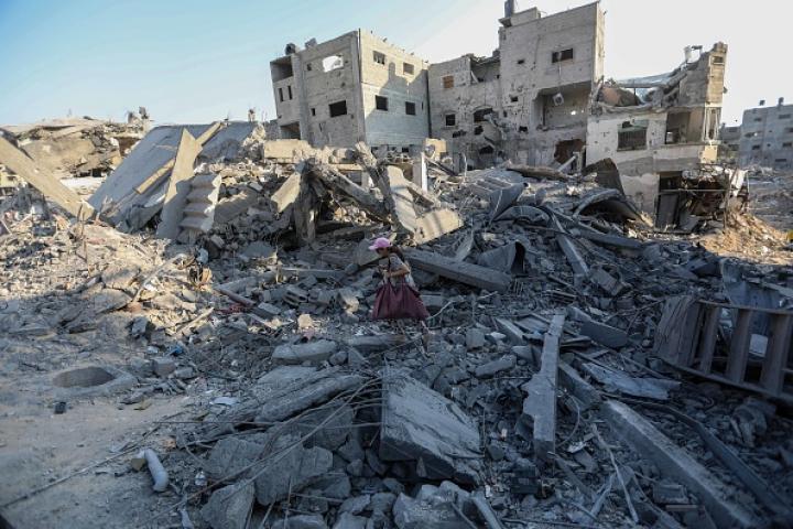 Imagen de archivo de una niña caminando con escasas pertenencias entre los restos de edificios bombardeados por el Ejército de Israel, en la Franja de Gaza.