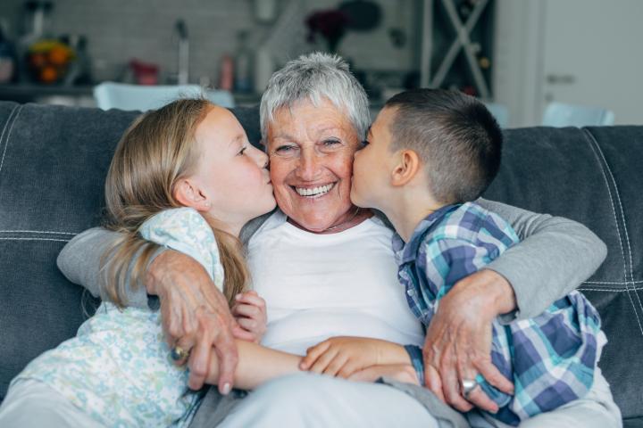 Una abuela recibiendo un beso de sus dos nietos.