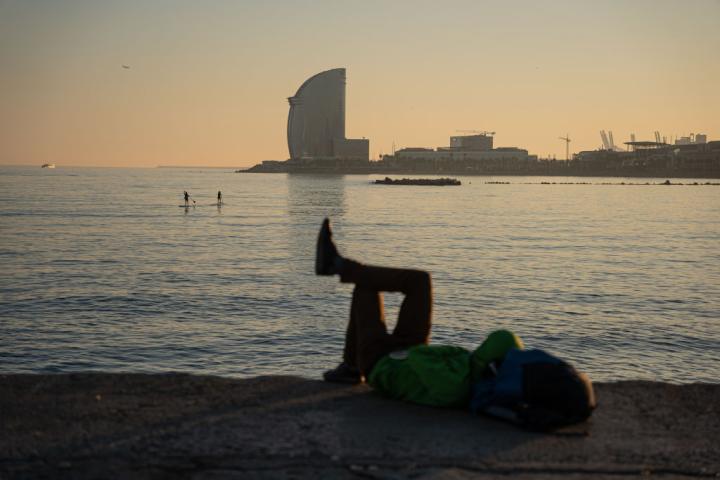 Varias personas disfrutan de un día soleado, junto al mar, en Barcelona
