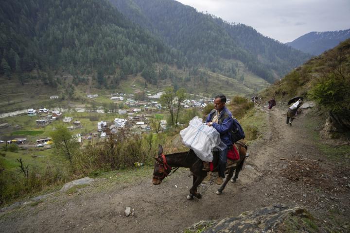 Un funcionario traslada a caballo una máquina de votación electrónica a una aldea de India.