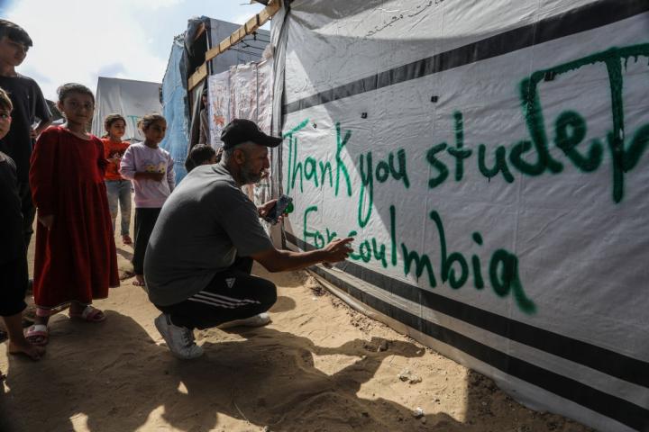 Un palestino hace una pintada en una tienda de campaña en Rafah en agradecimiento a las protestas estudiantiles en Estados Unidos.
