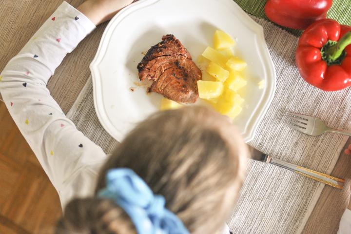 Imagen de archivo de una niña comiendo pescado.