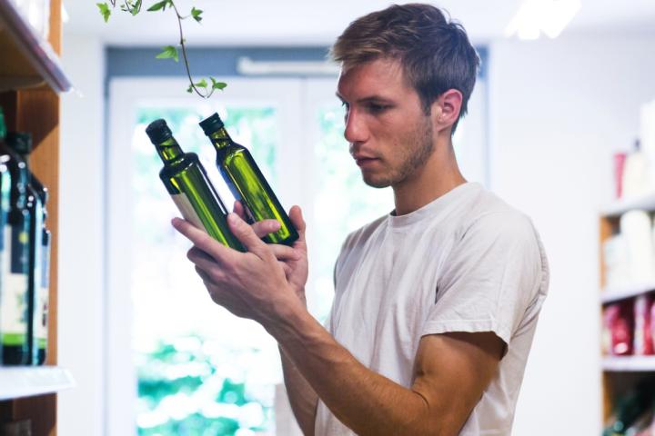 Un hombre compara varios tipos de aceite en el supermercado