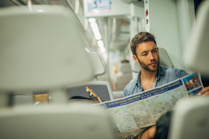 Un turista consulta un mapa de de España mientras viaja en tren.