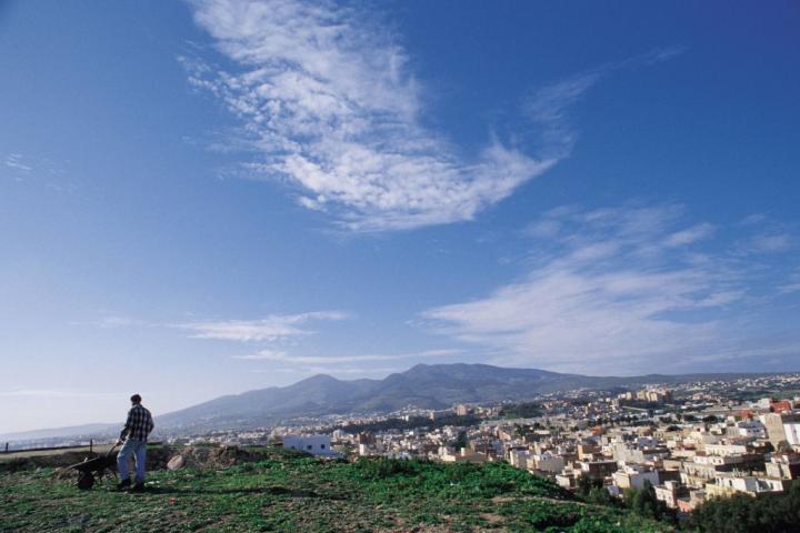 Un hombre con carretilla observa Melilla desde el Monte Gurugú, en Marruecos.