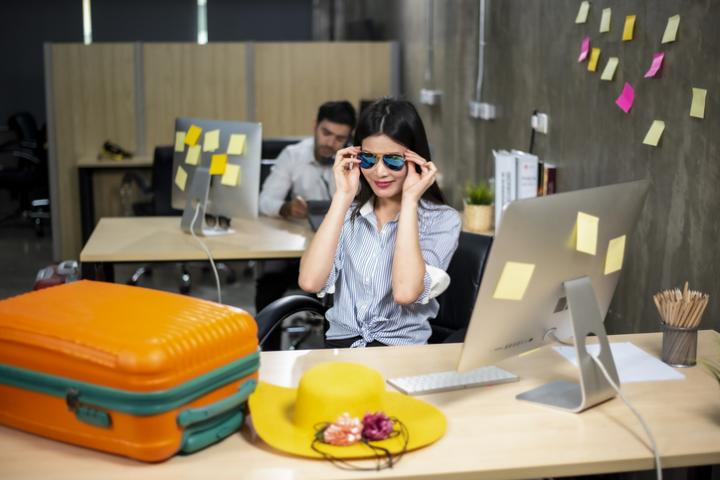 Una mujer con su maleta preparada en una mesa de oficina.