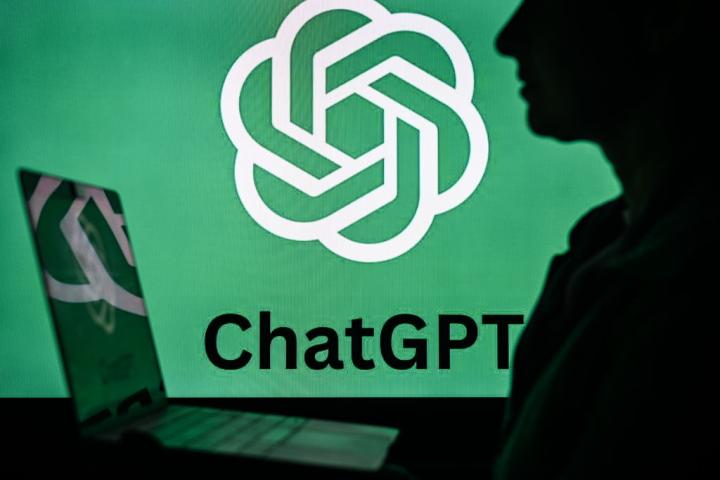 Una mujer sostiene un portátil delante de un logotipo de ChatGPT.