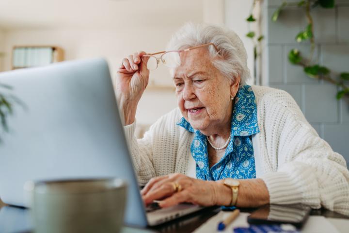 Imagen de archivo de una señora mayor comprobando algo en su portátil.