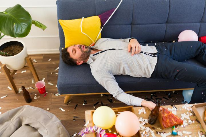 Imagen de archivo de un hombre tumbado en un sofá tras demasiada fiesta.