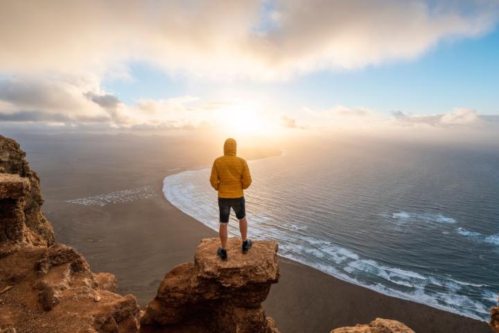 Persona admirando el atardecer en una playa de Lanzarote