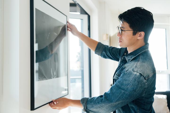 Un hombre colgando un cuadro.