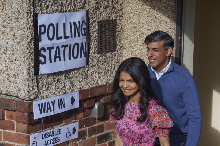 El candidato de los conservadores británicos, Rishi Sunak, abandona el colegio electoral junto a su mujer, Akshata Murty, después de votar este jueves.