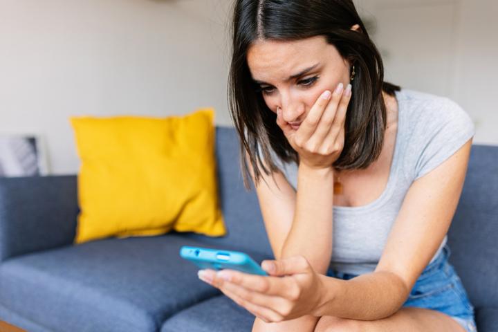 Imagen de una persona observando algo con preocupación en su teléfono móvil.