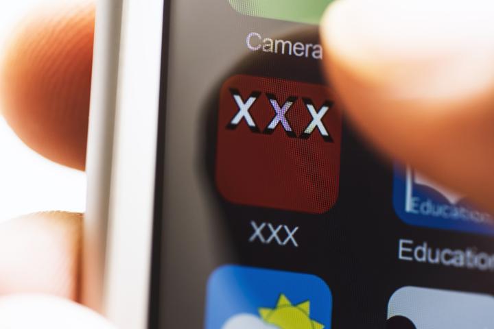 Una persona consumiendo pornografía con su teléfono móvil.