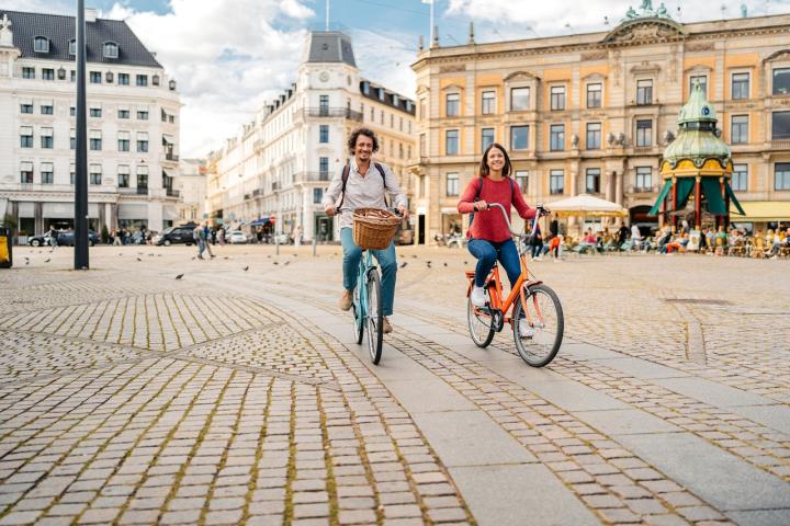 Dos turistas pasean en bicicleta por las calles de Copenhague.