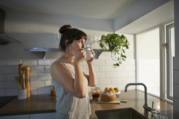 Una mujer tomando un café en su casa.