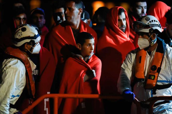 Niño migrante acompañado de otro migrante esperando desembarcar de un barco de rescate español tras su llegada al puerto de Málaga.