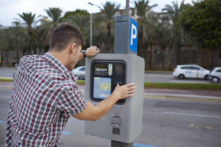 Un hombre pagando en un parquímetro.