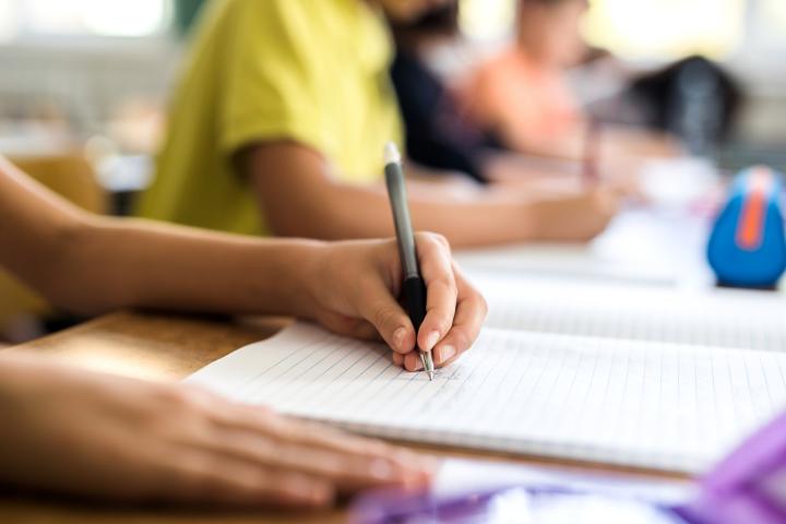 Un niño zurdo escribiendo en clase.