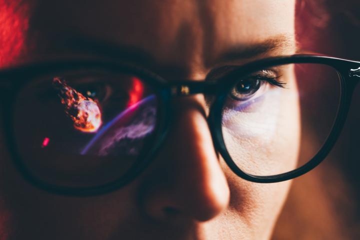 Recreación digital de un asteroide reflejado en el cristal de las gafas de una persona.
