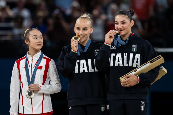 alt="alt="La ganadora de la plata en la barra de equilibrio, la china Yaqin Zhou of China, protagonizó una de las escenas más tiernas sobre el podio al morder su medalla, imitando el gesto de las italianas.""