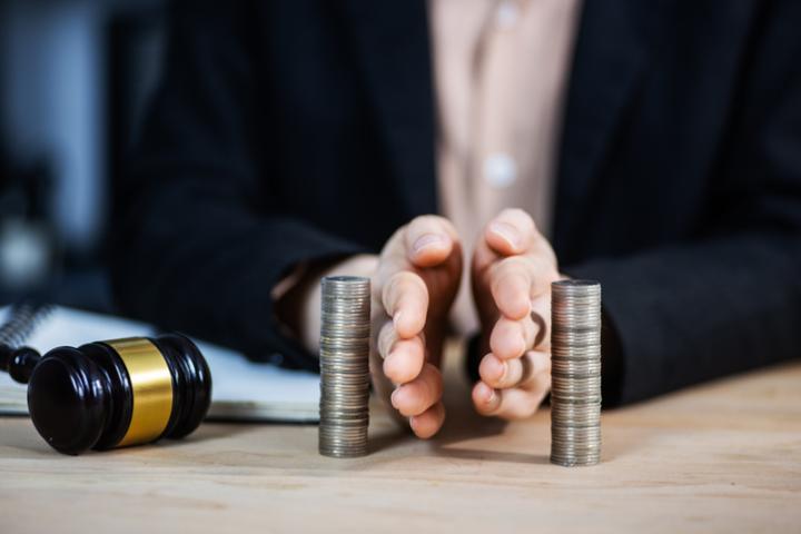 Imagen de archivo de una mesa con un mazo y unas manos dividiendo dinero.