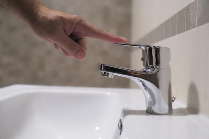 Imagen de archivo de una persona cortando el agua de un grifo.