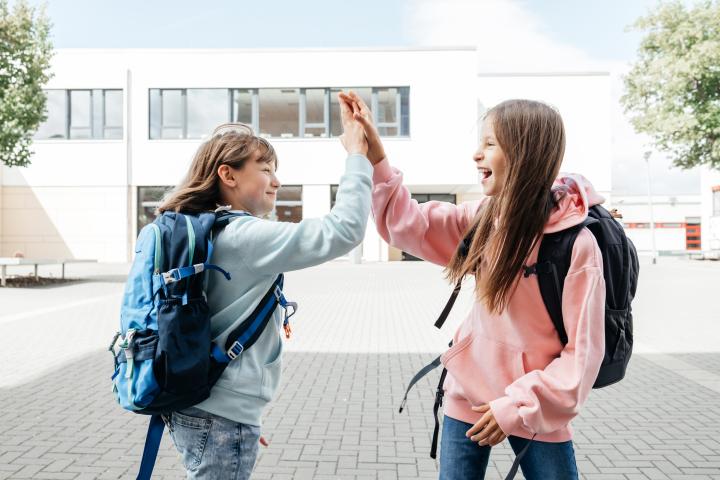 Unas niñas chocándose la mano en su vuelta al cole.